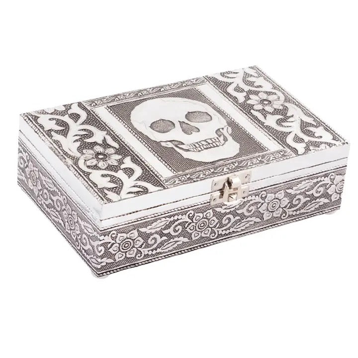 A rectangular silver-toned jewelry box with an engraved skull design on the lid and ornate floral scrollwork borders, shown on a plain white background.