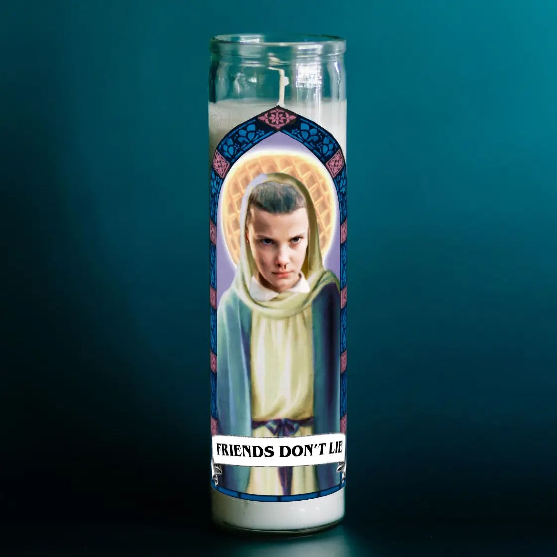 Candle with a printed design of a person and 'Friends Don't Lie' text on a dark background