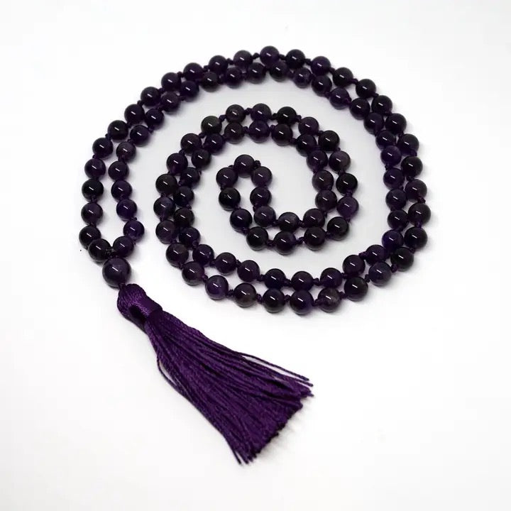 Purple beaded necklace with a tassel on a white background