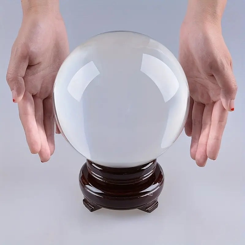 Crystal ball on a wooden stand with hands reaching towards it against a light gray background
