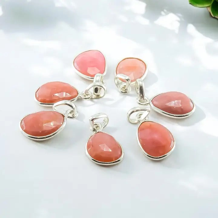 Set of pink stone pendants on silver chains against a white background