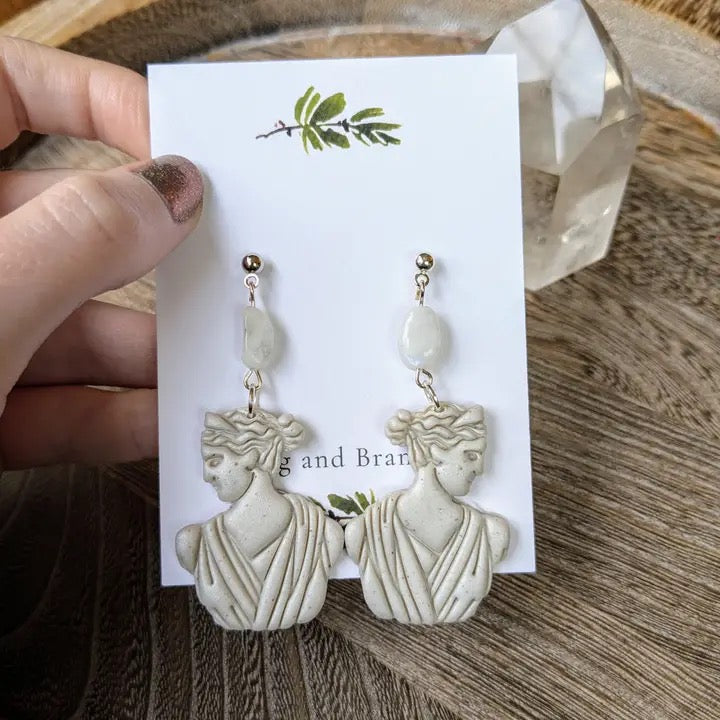 Pair of earrings on a card held by a hand on a wooden surface