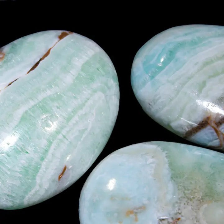 Three green marbled stones on a black background