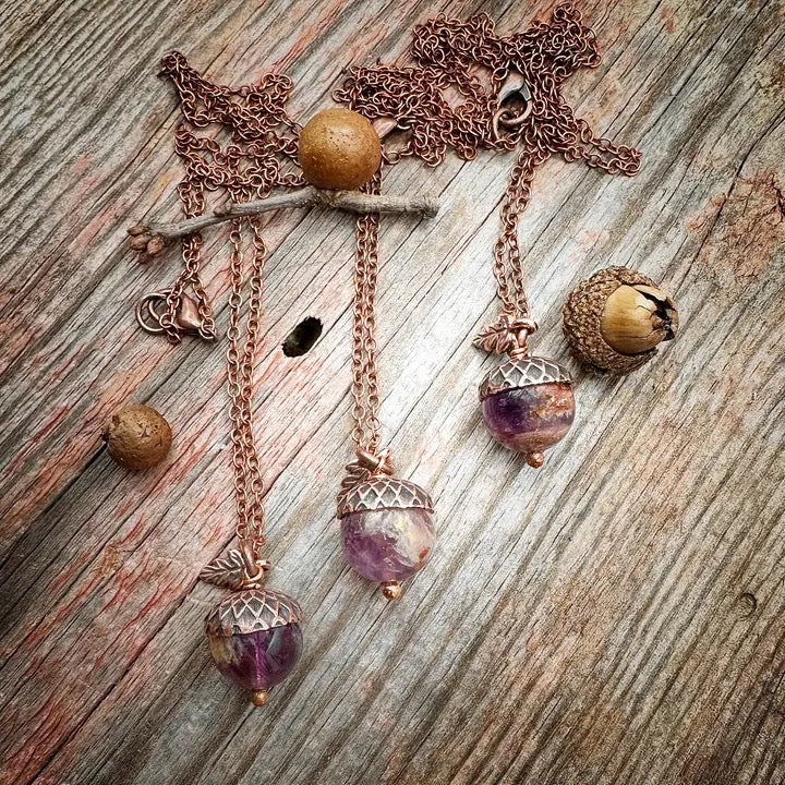 Necklace with acorn and gemstone pendants on a wooden surface