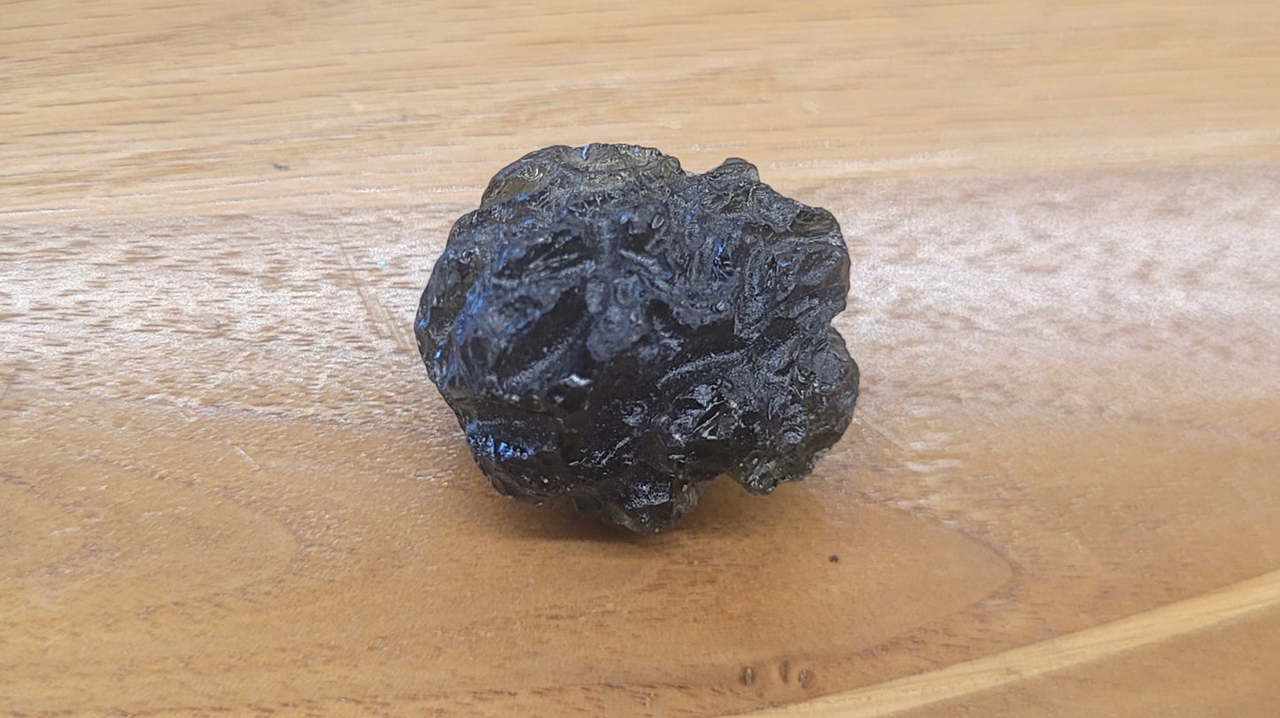 Black mineral or fossil on a wooden surface