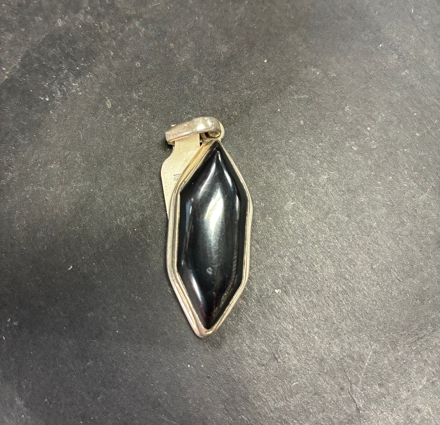 Black stone pendant on a dark gray surface