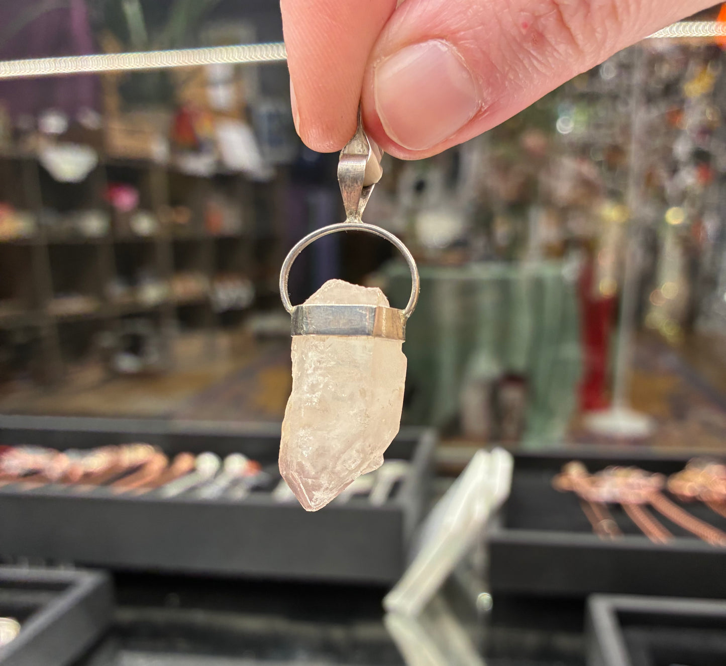Crystal pendant held by a hand with a blurred store background