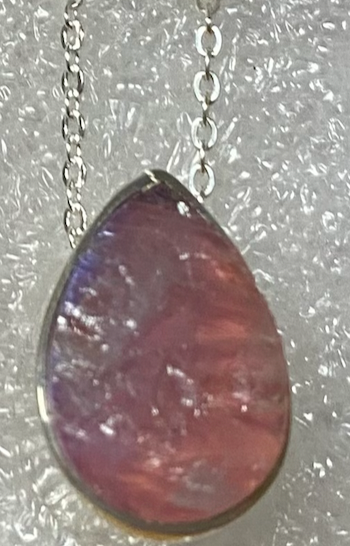 Teardrop-shaped purple stone pendant on a silver chain against a textured gray background