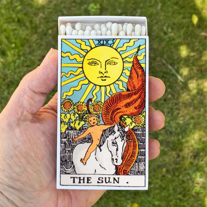 matchboxes feature the Sun Tarot Card on both sides, held by a hand.