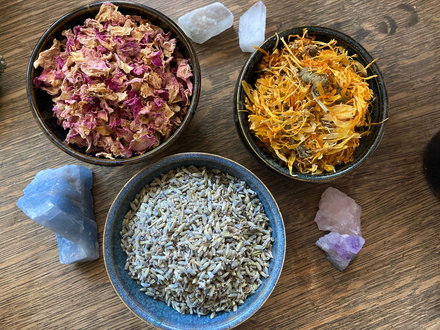 Herbs in three bowls calendula, lavender, rose petals and a few crystals