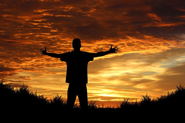 Person outstretched arms to a sunset