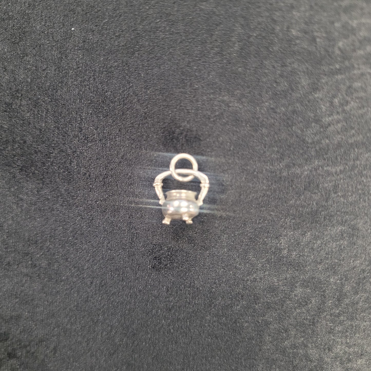 Small silver charm on a clear string against a dark background