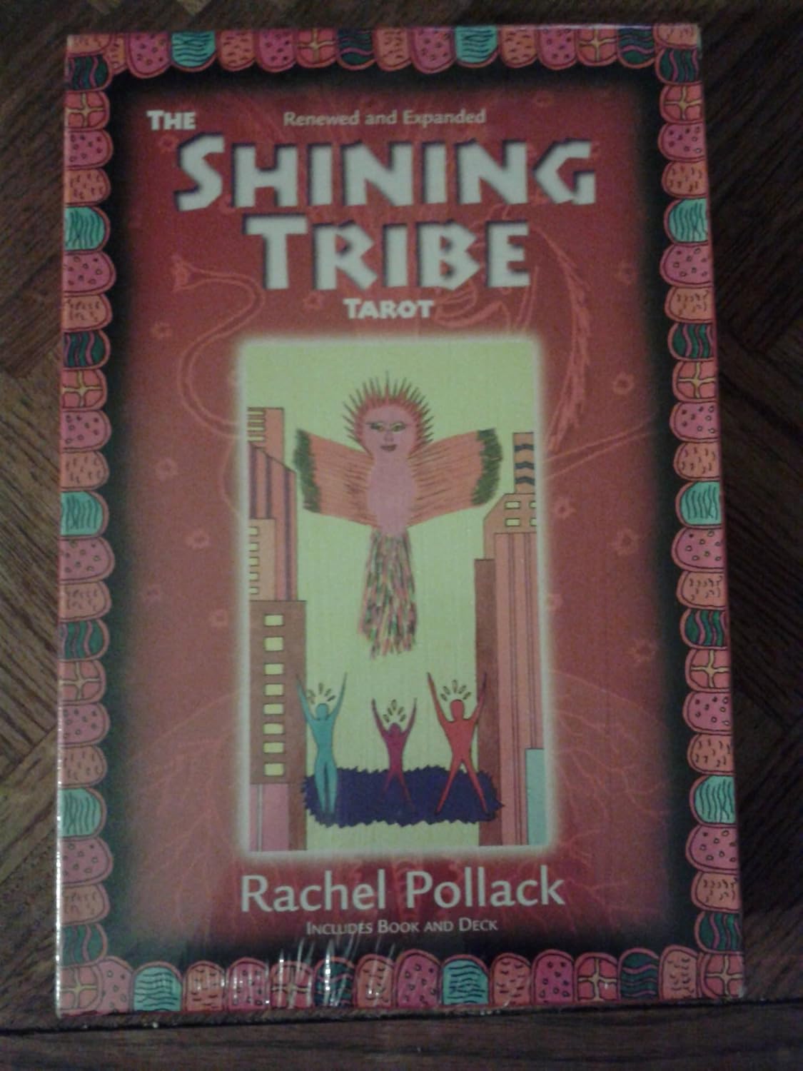 Box of 'The Shining Tribe Tarot' by Rachel Pollack with colorful design on a wooden surface.