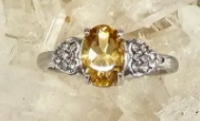 Silver ring with a yellow gemstone on a textured beige background