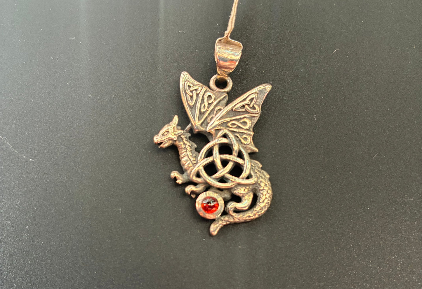 Sterling silver dragon with a triquetra symbol and a red garnet gemstone.