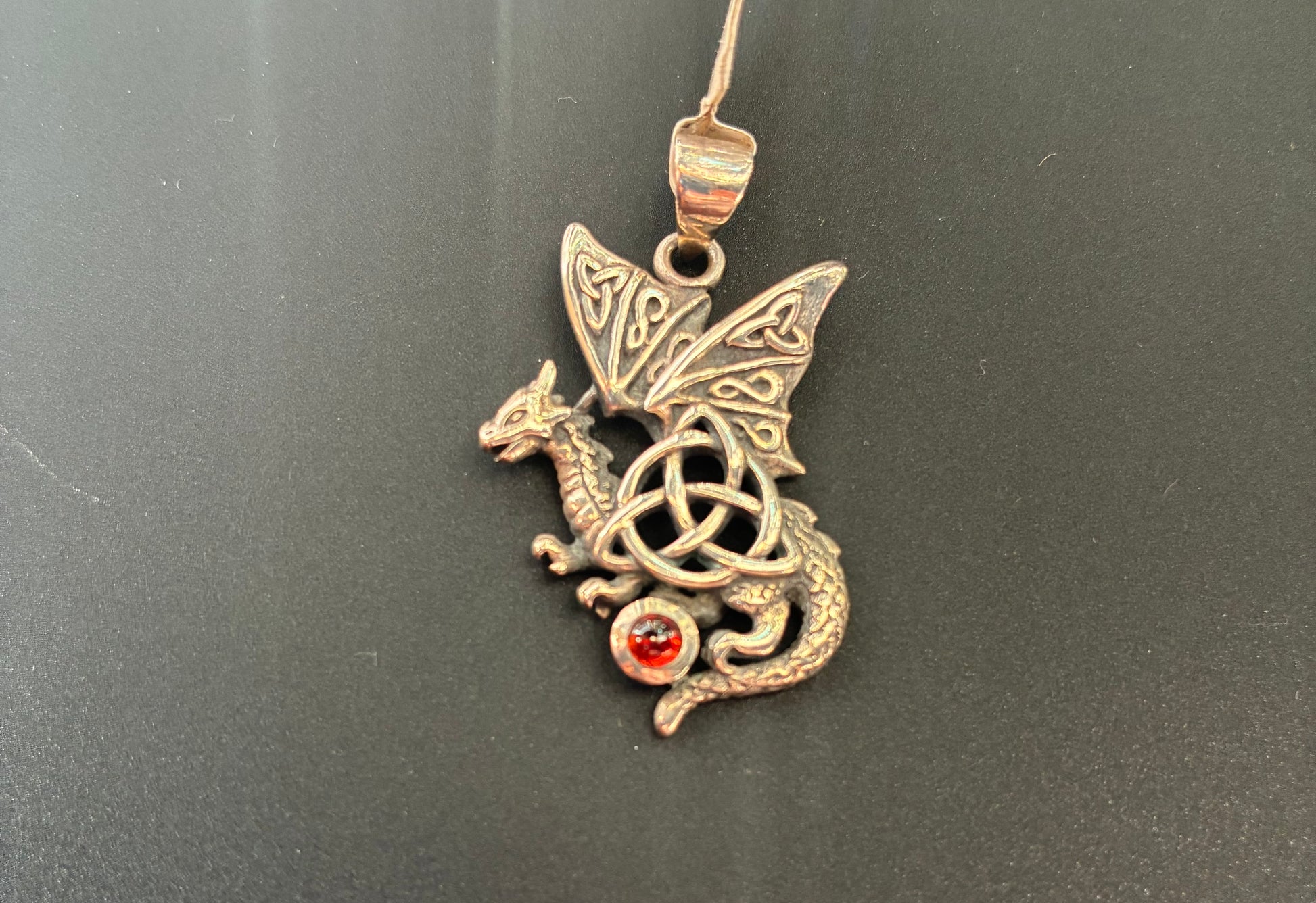 Sterling silver dragon with a triquetra symbol and a red garnet gemstone.