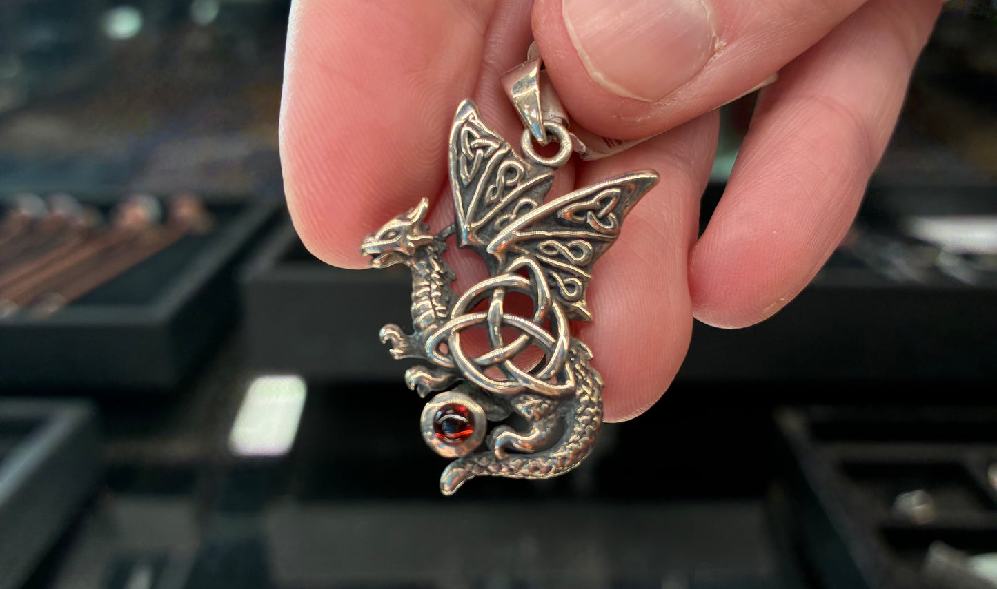 Sterling silver dragon with a triquetra symbol and a red garnet gemstone.