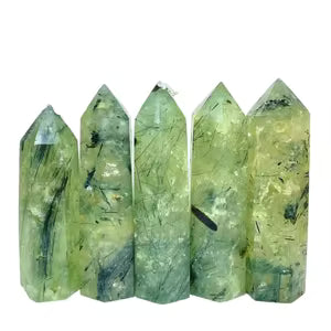 Group of prehnite towers; green with black inclusions on white background.