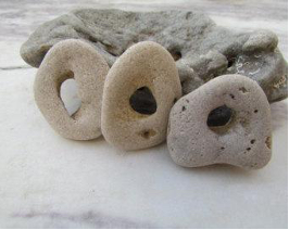 Three stone donuts with holes on a stone surface