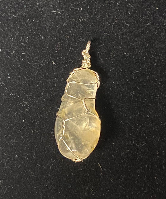 A small teardrop-shaped translucent quartz stone pendant wrapped in silver-toned wire, shown on a black textured background.