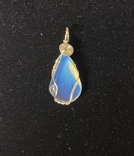 A teardrop-shaped opalite pendant wrapped in silver-toned wire, featuring a spiral wrap detail at the bail, shown on a textured black background.