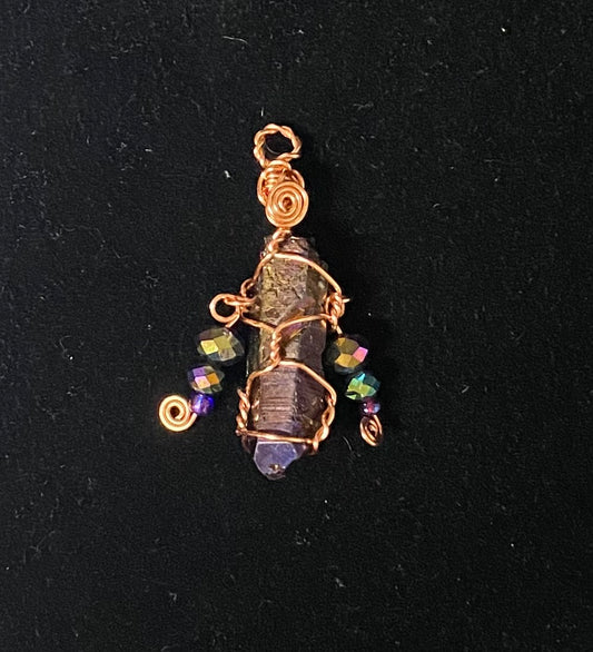 A handmade wire-wrapped pendant featuring a purple titanium purple quartz point, accented with small iridescent purple and green beads and copper-colored spiral wire details, set against a black background.