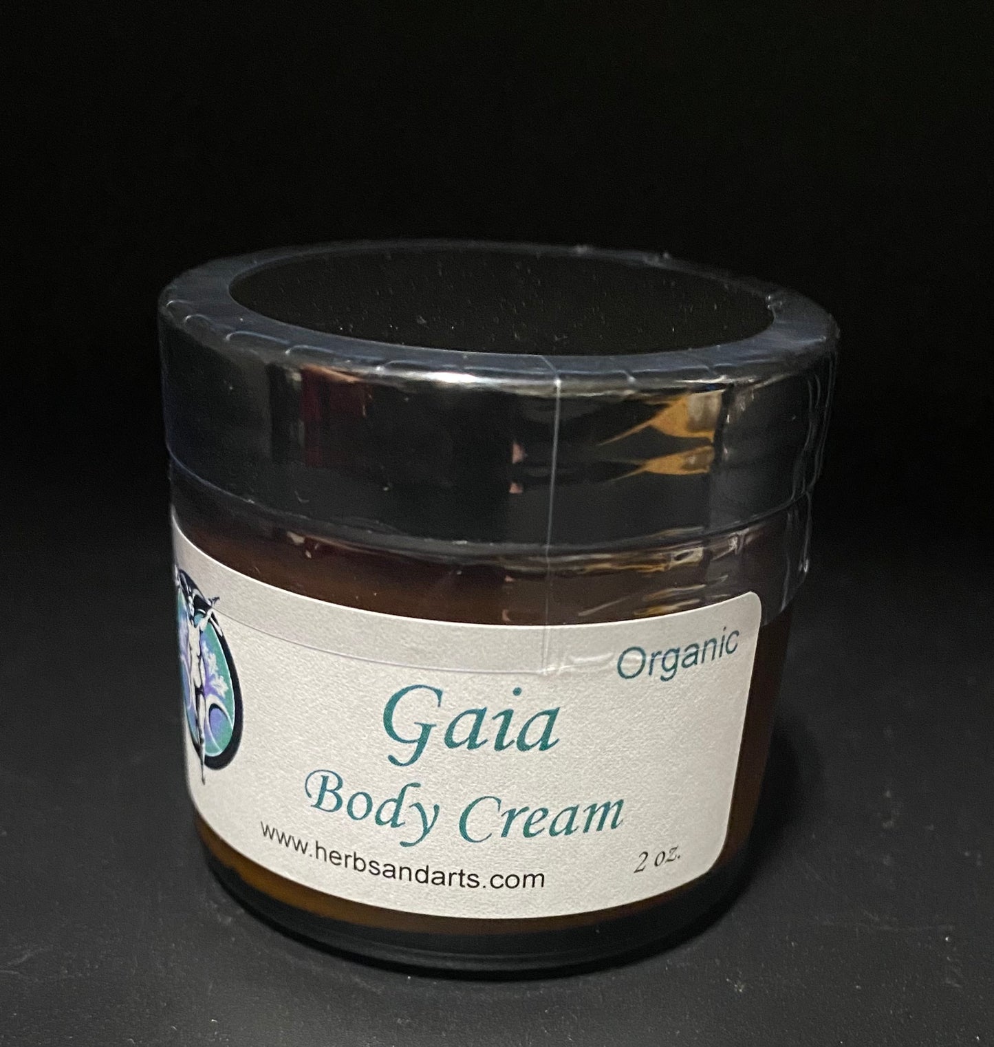A 2 oz jar of Gaia Body Cream by Herbsandarts, featuring an organic label on a dark background.