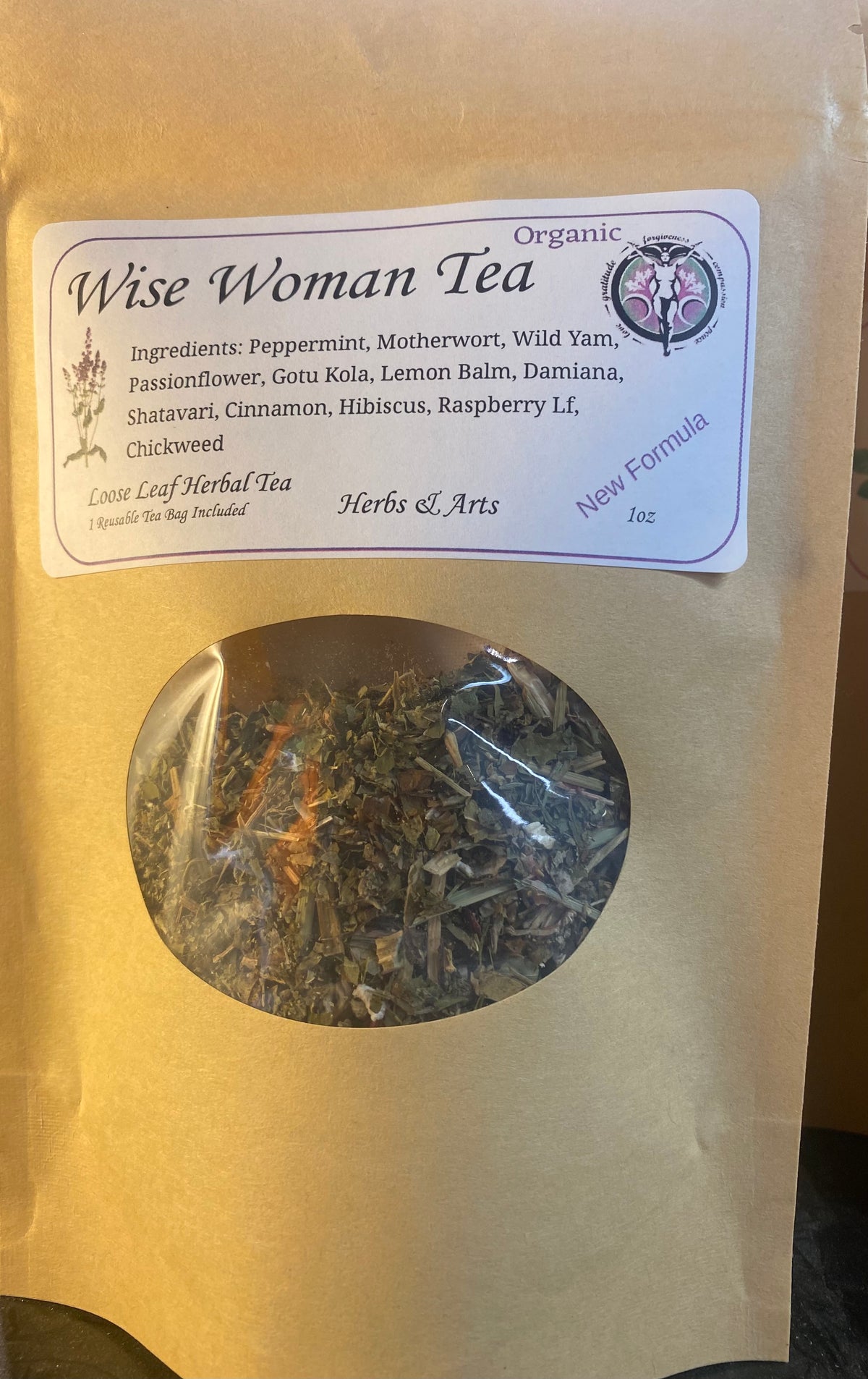 A kraft paper stand-up pouch of Wise Woman Tea with a clear oval window showing loose herbal tea inside. The front label reads Organic Wise Woman Tea and lists ingredients such as peppermint, motherwort, wild yam, passionflower, gotu kola, lemon balm, damiana, shatavari, cinnamon, hibiscus, raspberry leaf, and chickweed.