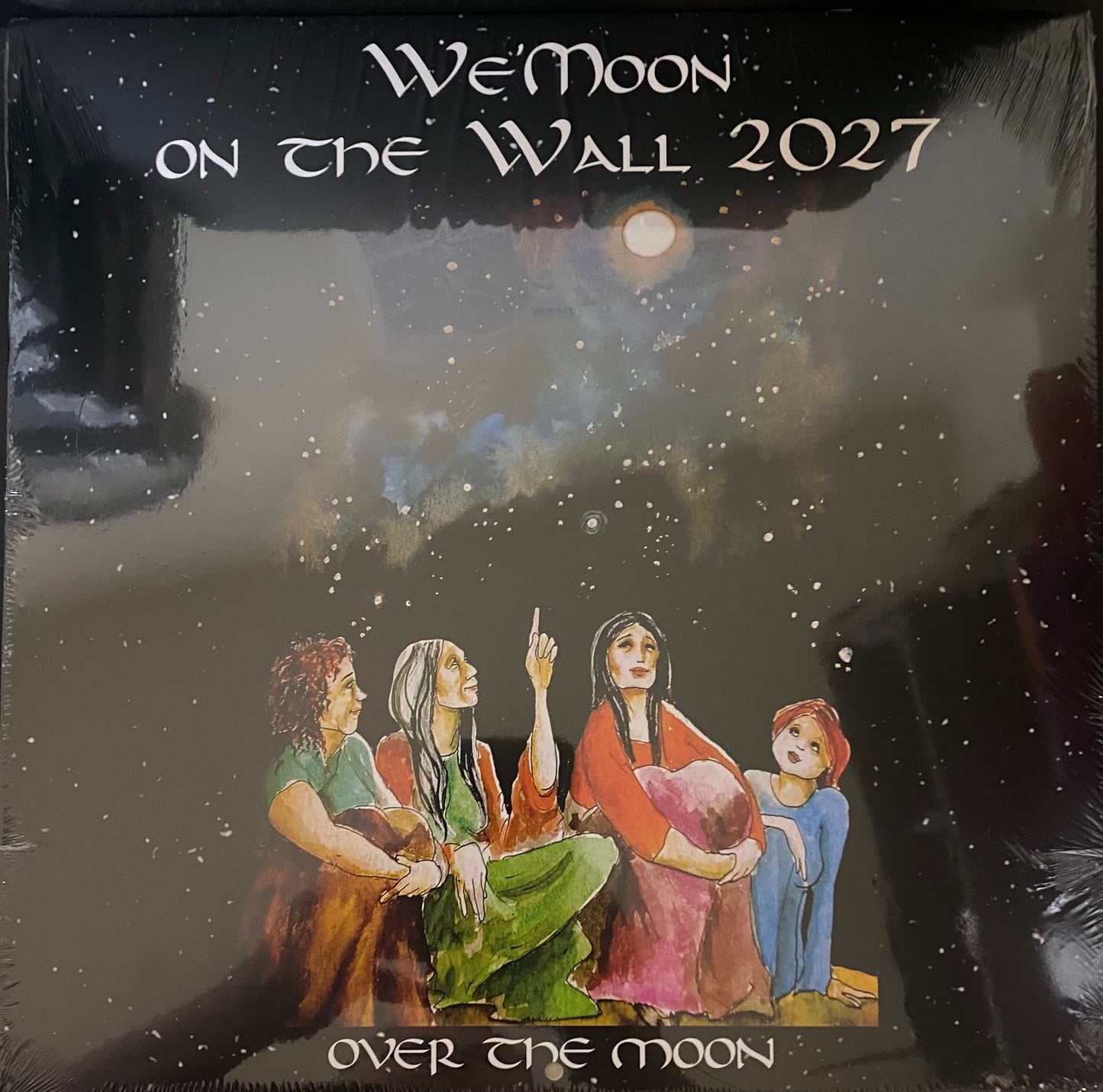 A square album or print cover featuring the title 'We'Moon ON THE WALL 2027' at the top and 'OVER THE MOON' at the bottom. The artwork shows four people sitting under a starry night sky with a glowing moon, in muted earthy and pastel tones.