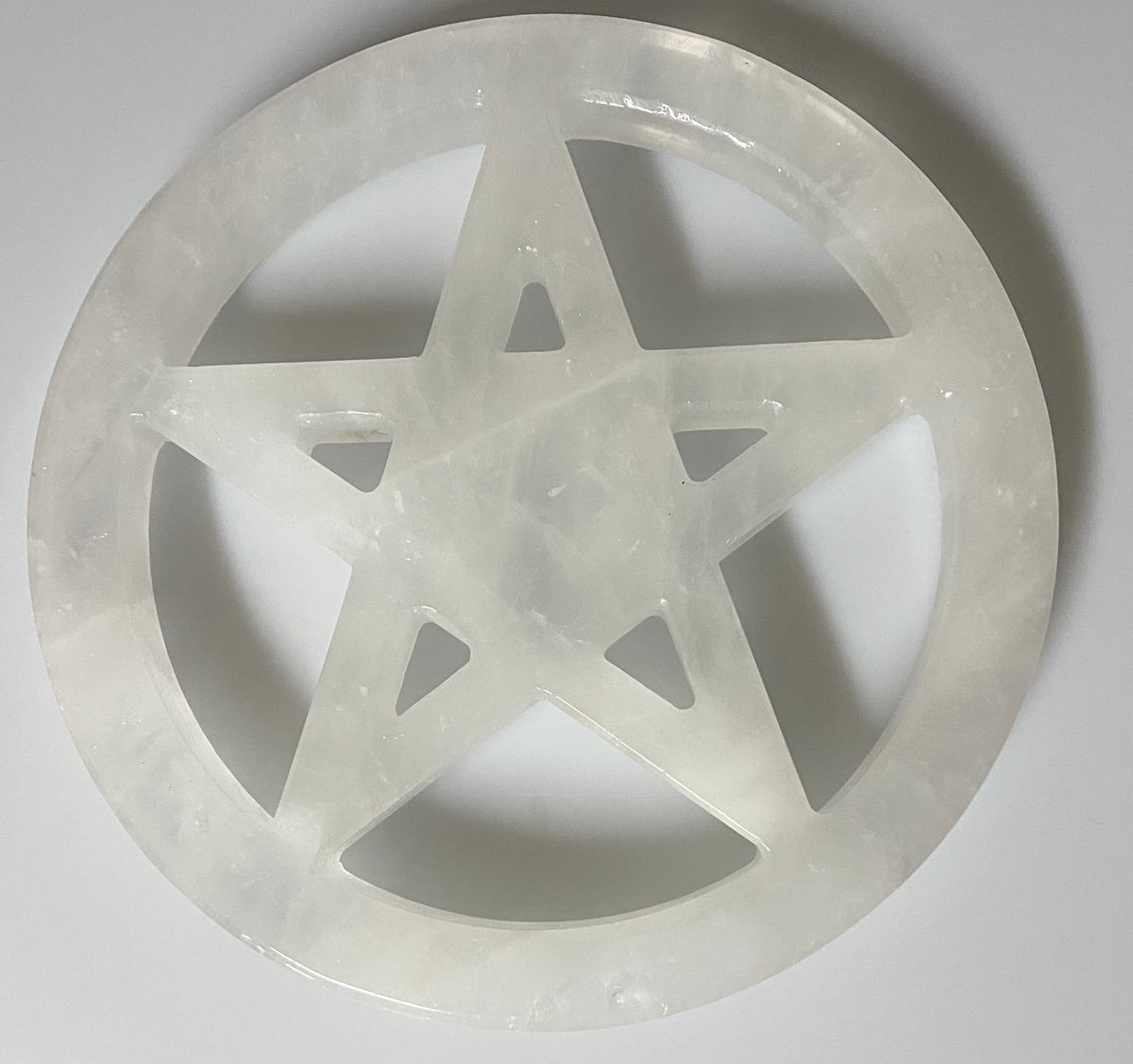 A circular clear quartz carved wall plaque featuring a five-pointed star design, photographed against a neutral light gray background.
