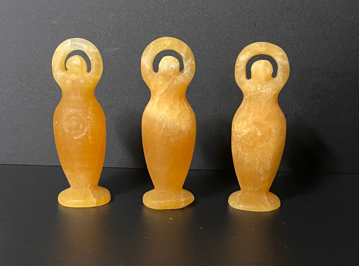 Three Orange Calcite Goddess Carvings on a a black background
