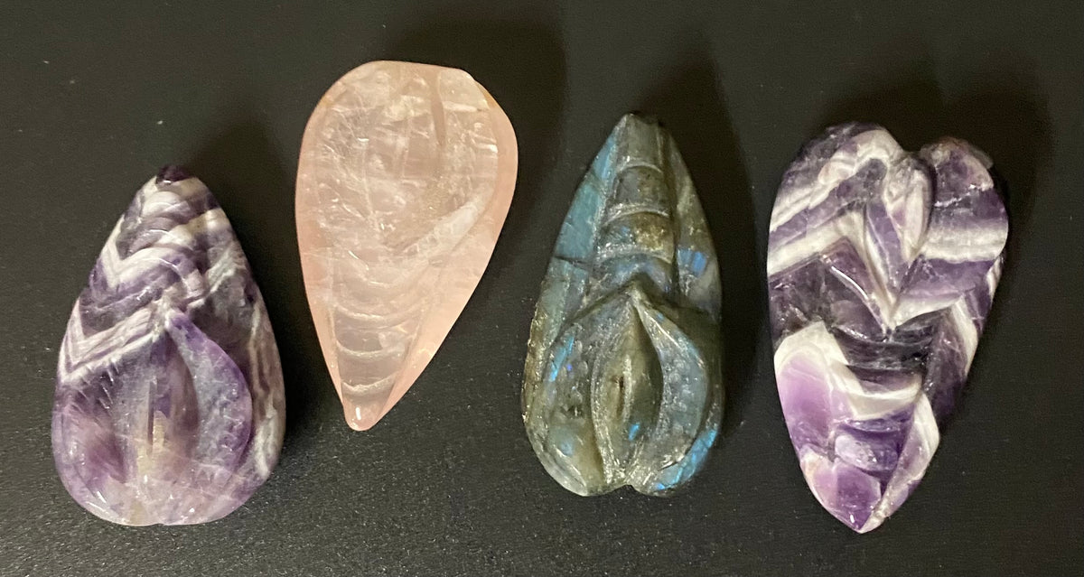 Vulva carved stone amulets on a black background