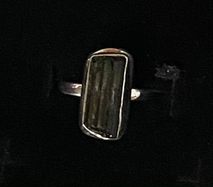 A silver-toned ring featuring a large, vertically striped dark green stone, shown against a solid black background.