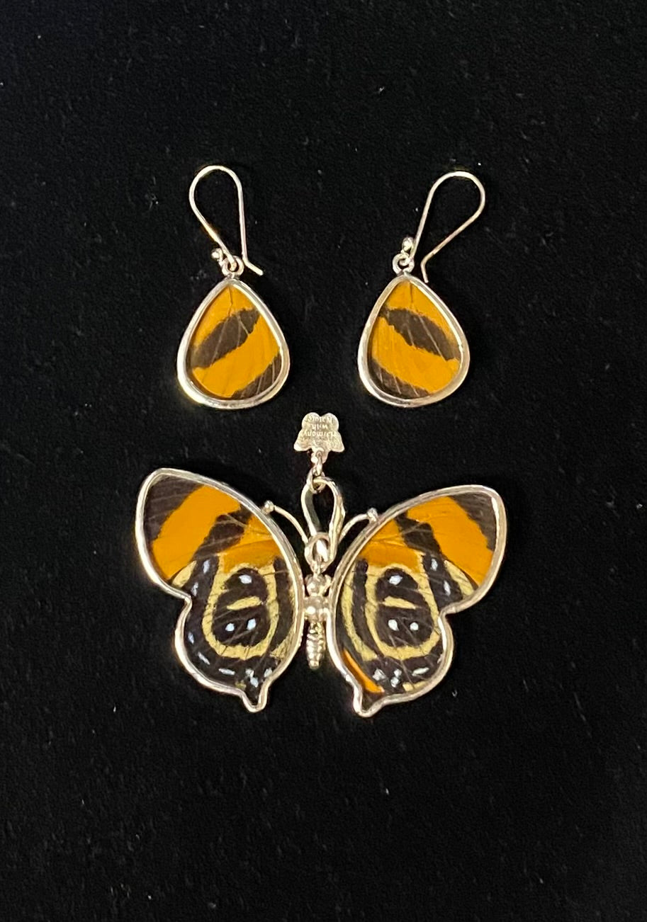 A butterfly and teardrop earring set featuring vibrant orange, black, and yellow butterfly wings set in silver-tone metal, displayed on a black background.