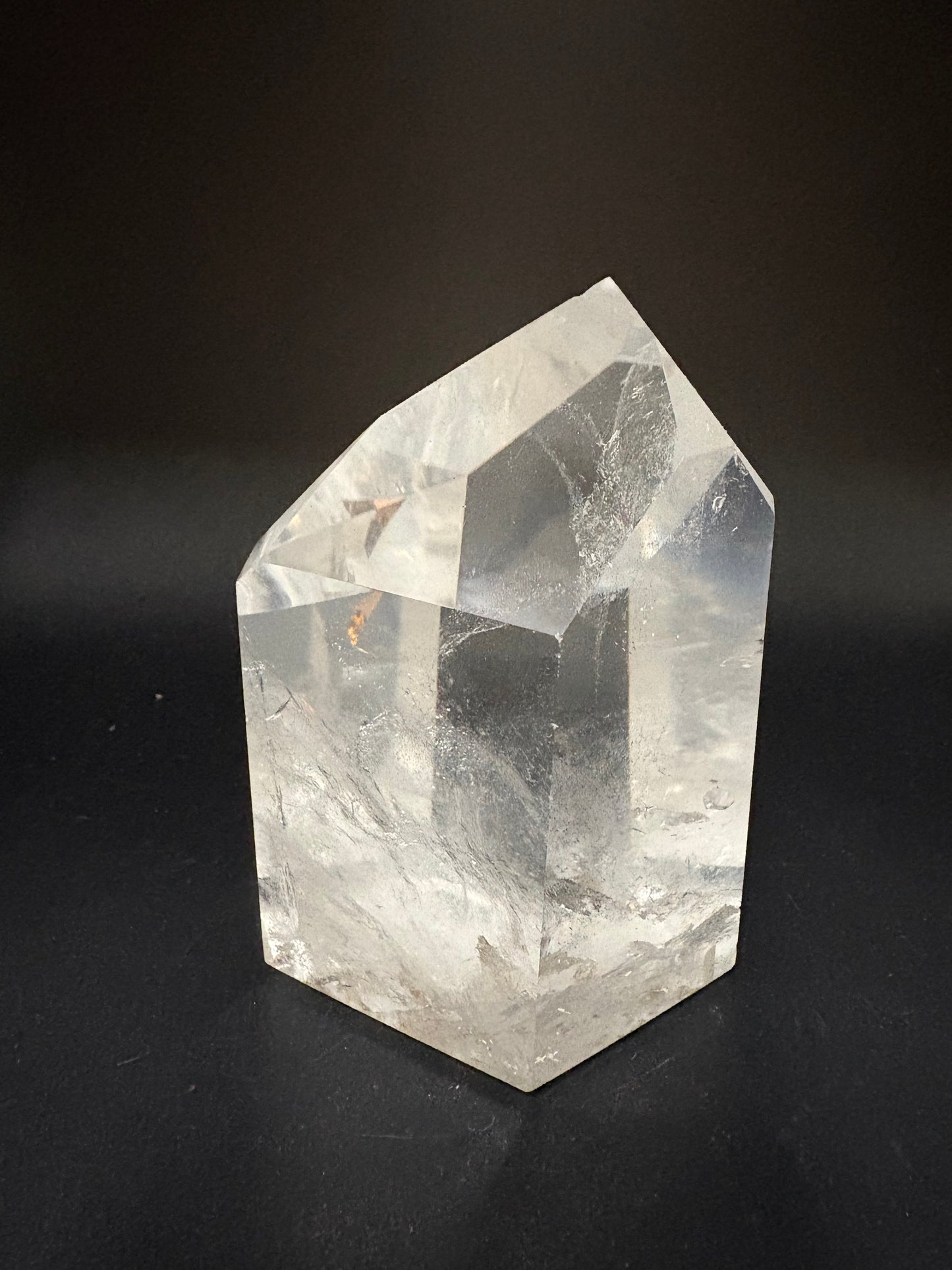 A faceted clear crystal stone, likely quartz, displayed on a dark black background.