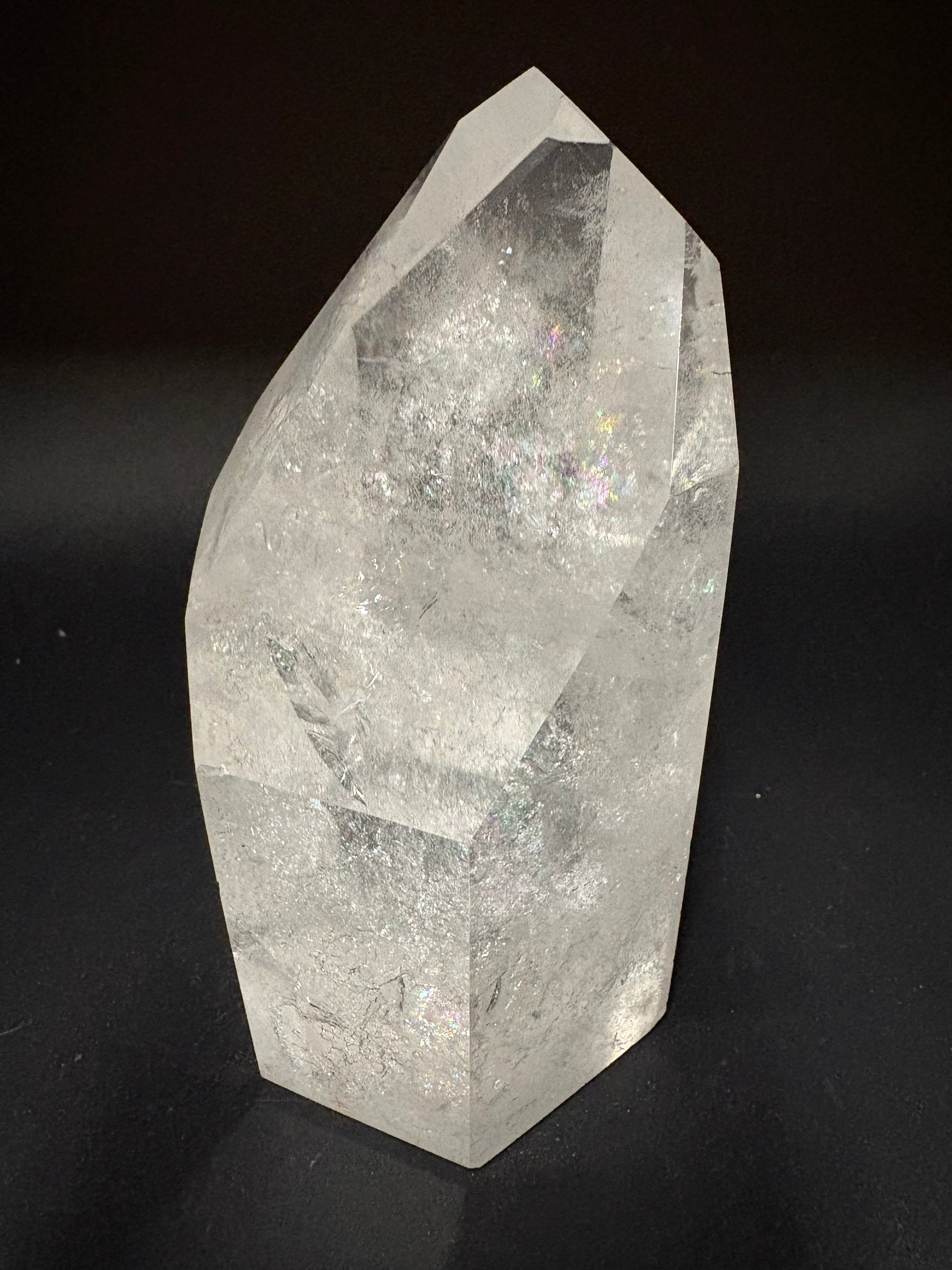 A faceted clear quartz crystal point with natural internal inclusions, photographed on a solid black background.