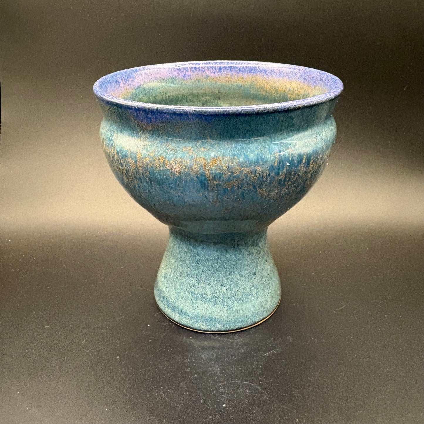 Denim blue ceramic pedestal bowl with purple rim on grey background