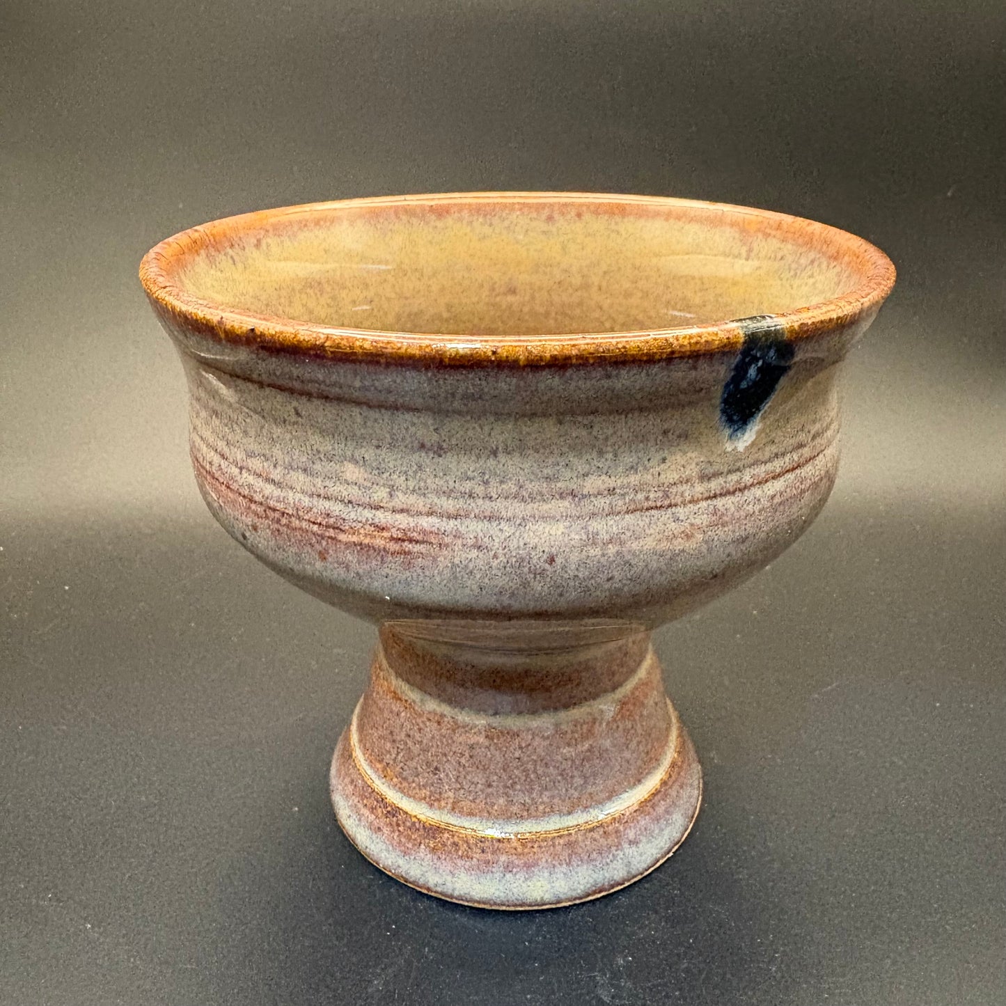 Mottled brown-cream ceramic pedestal bowl on grey background