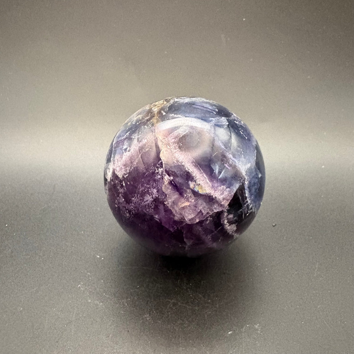 Blue and purple polished fluorite sphere on black background