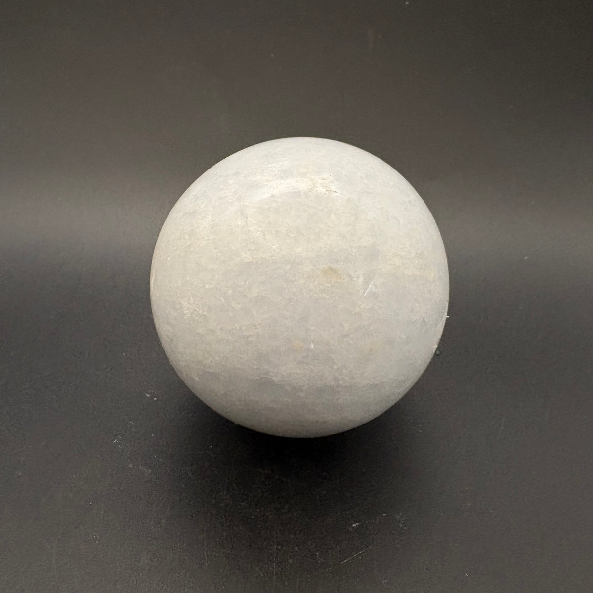 white crackled calcite sphere on gray background