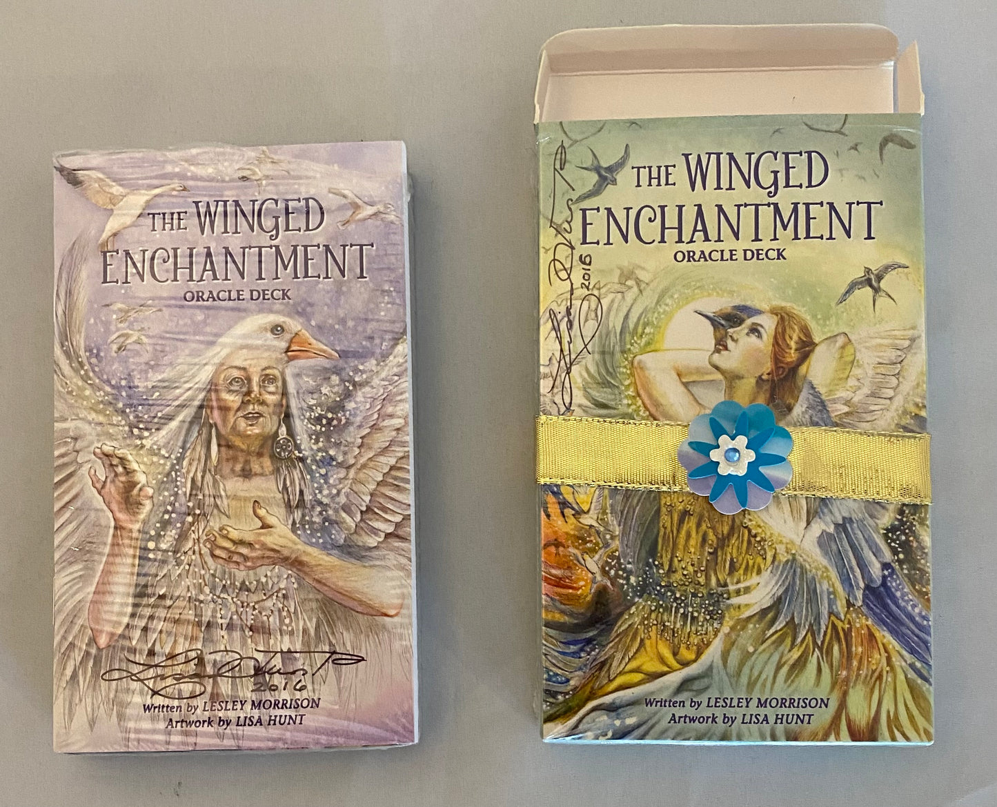 Two 'The Winged Enchantment' Oracle Deck packaging on a gray background