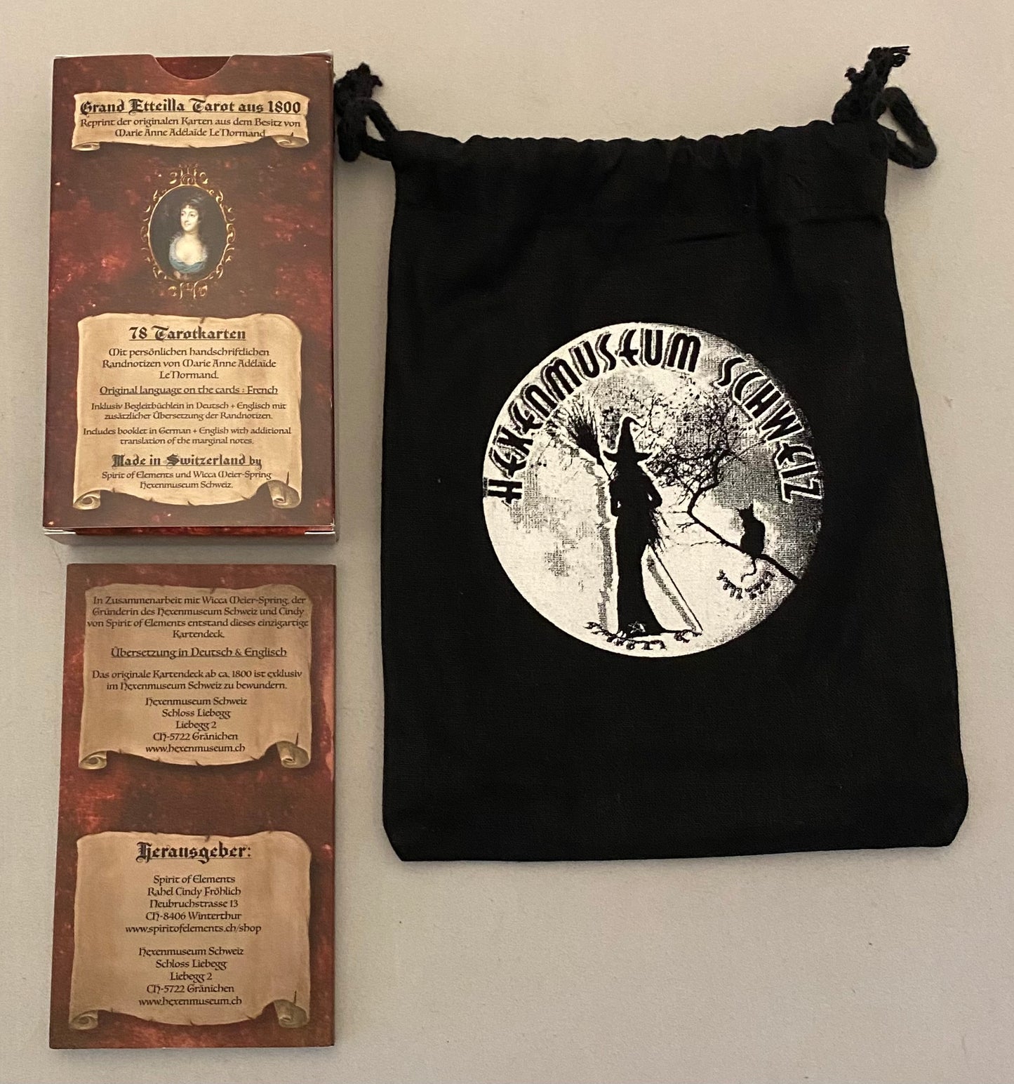 Black drawstring bag with a circular design featuring two figures and text, next to two brown cards with similar designs.