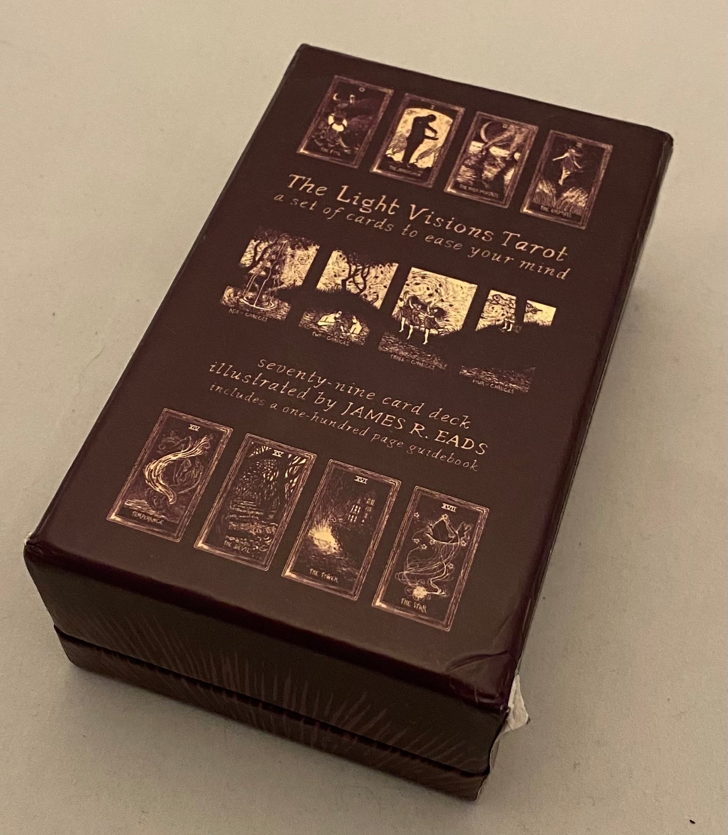 Brown tarot card box with gold illustrations on a light gray background