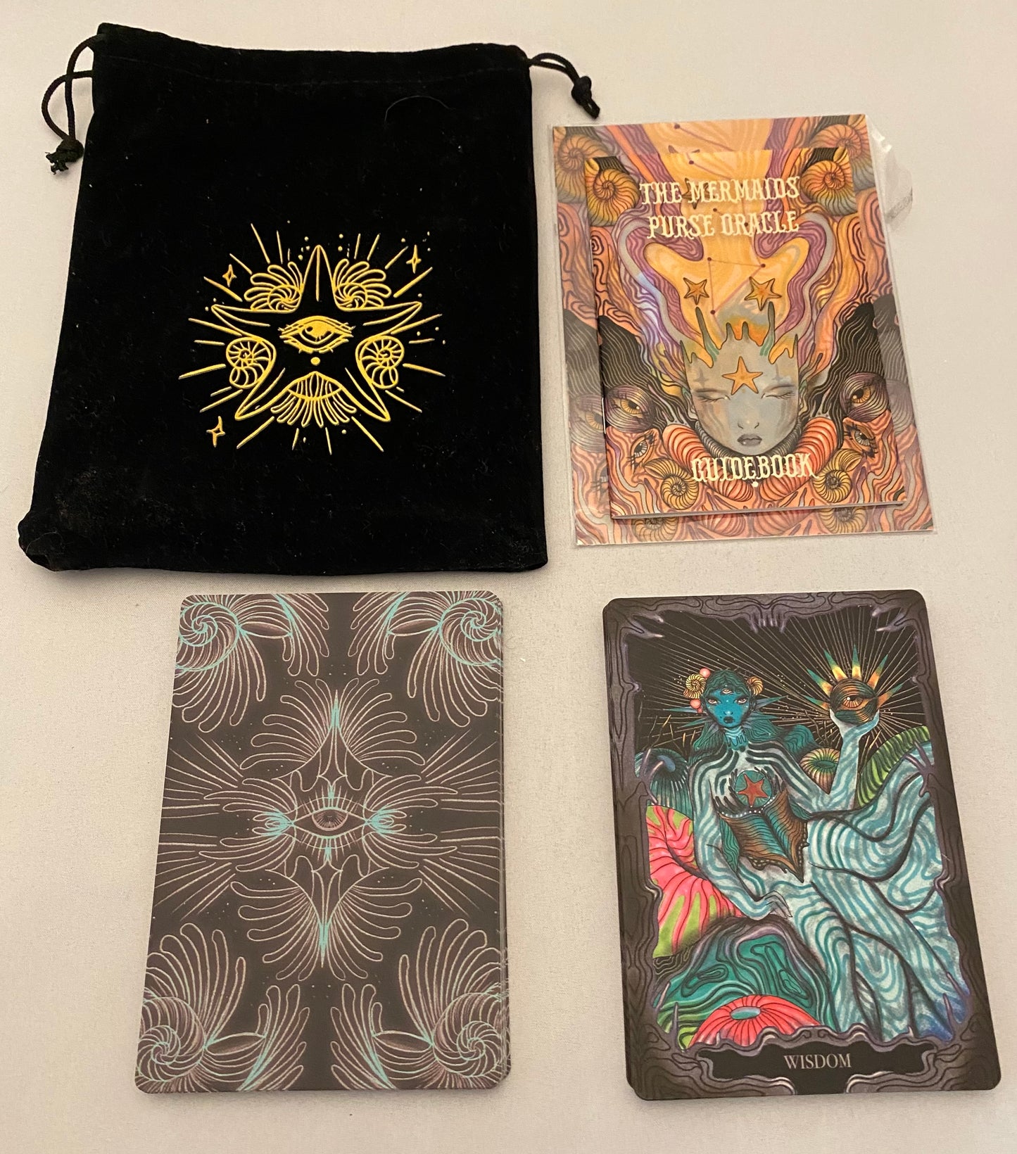 Set of tarot cards with a black drawstring bag and guidebook on a light gray background