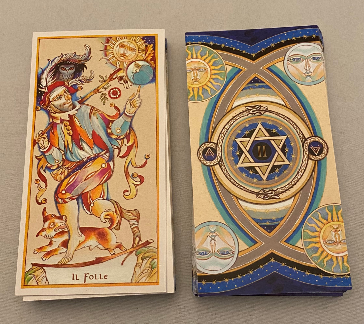 Two tarot cards with intricate designs on a gray background