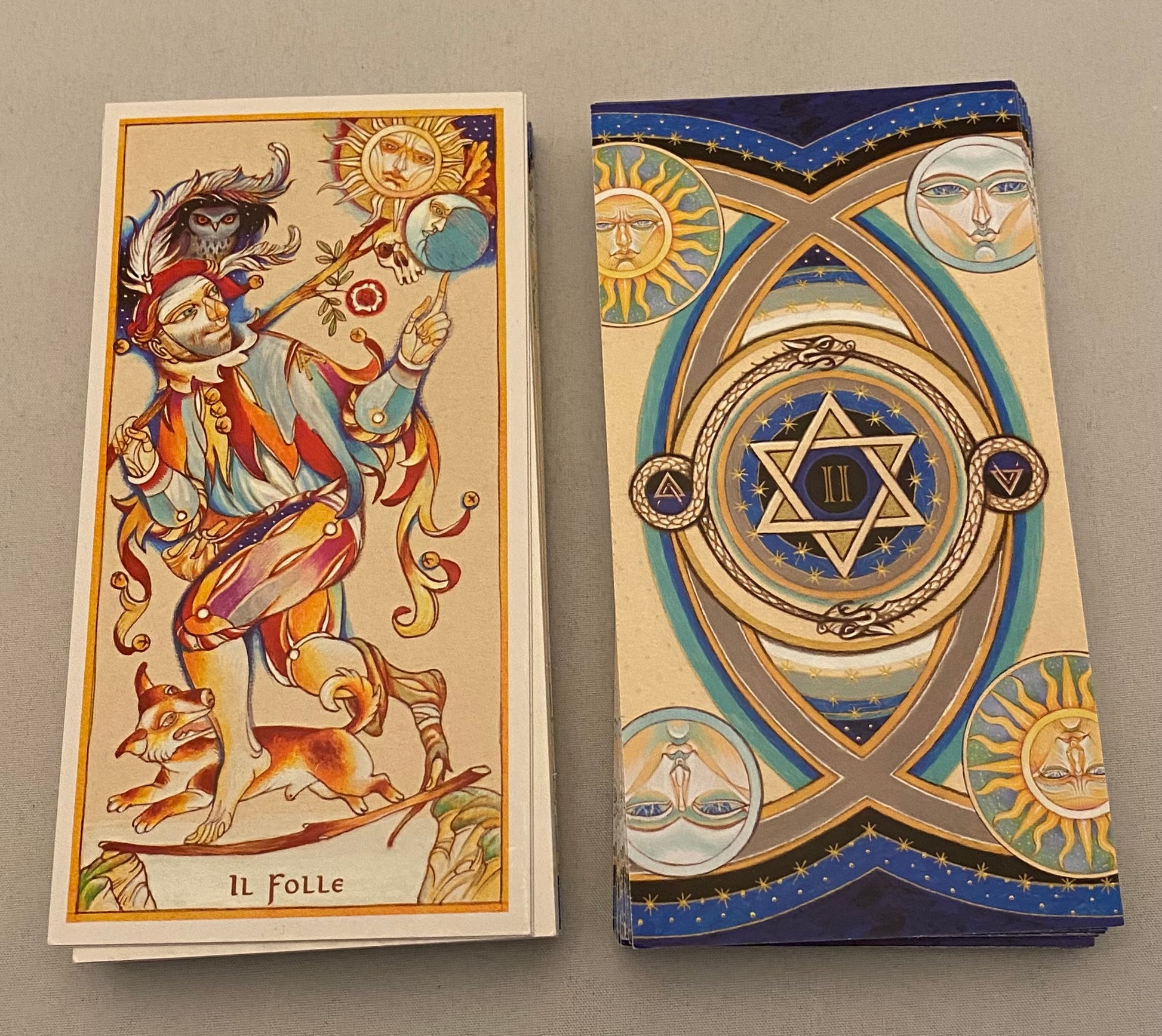 Two tarot cards with intricate designs on a gray background