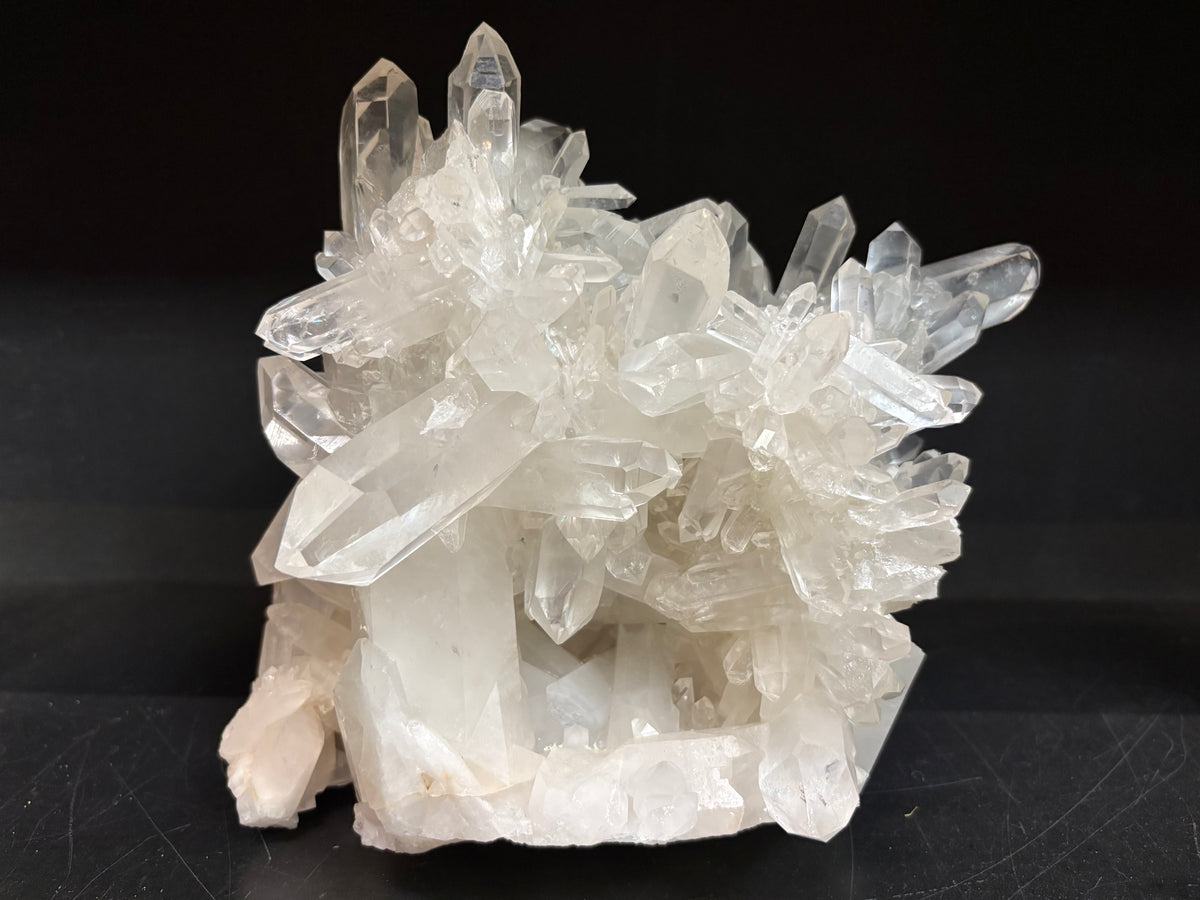 A cluster of clear quartz crystal points on a white matrix, photographed against a solid black background.