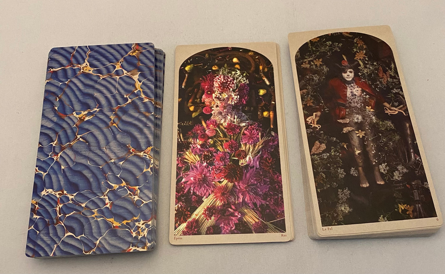 Three tarot cards with artistic designs on a plain background