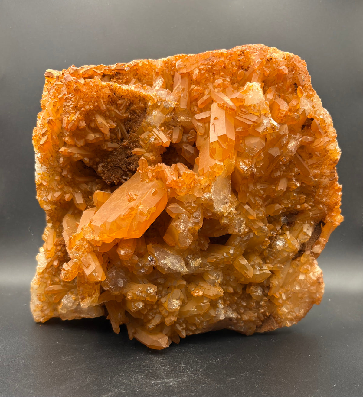 A natural Tangerine Quartz crystal cluster specimen with multiple faceted translucent crystal points on a dark gray background.