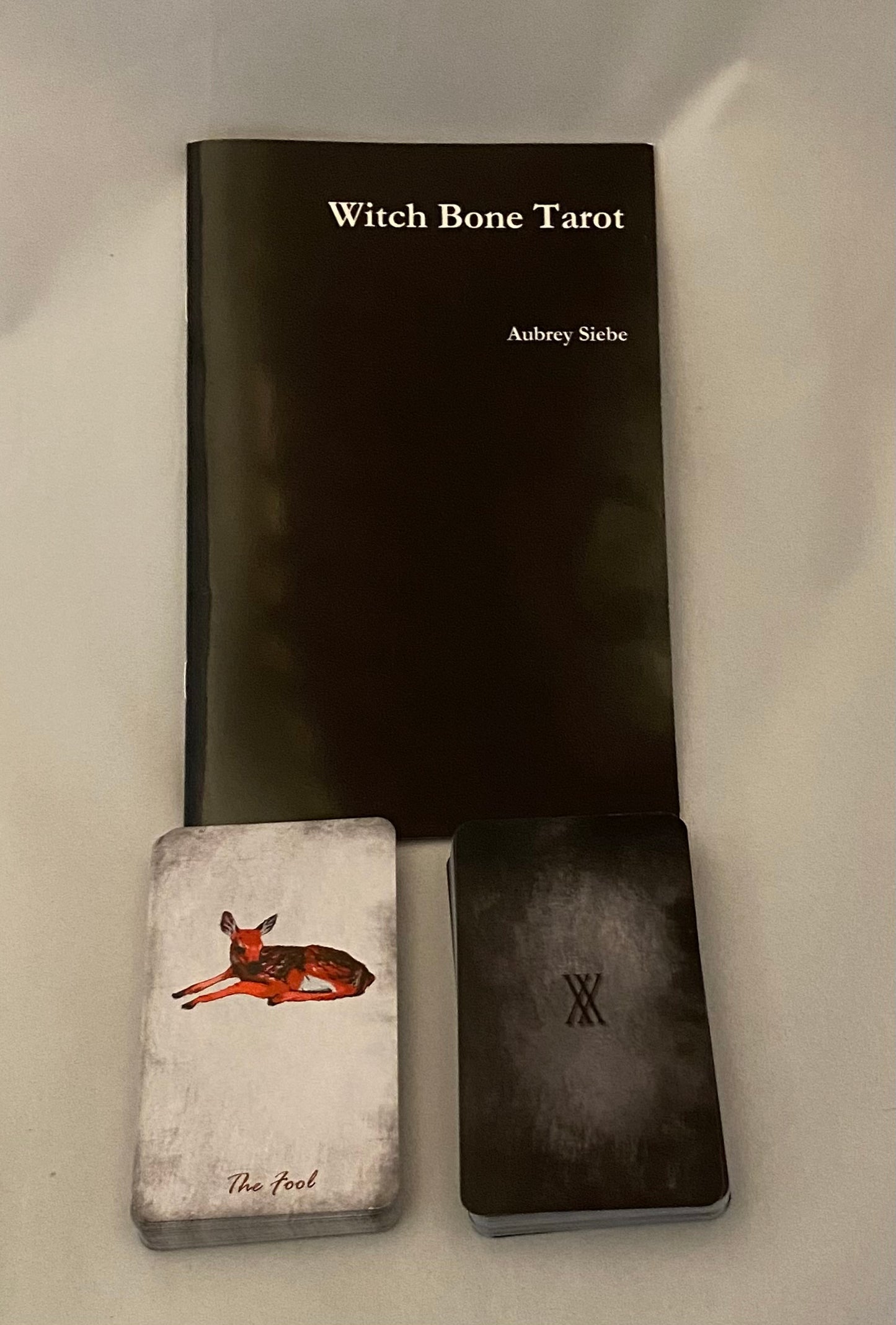 Witch Bone Tarot set with black book, small card, and black box on a white background